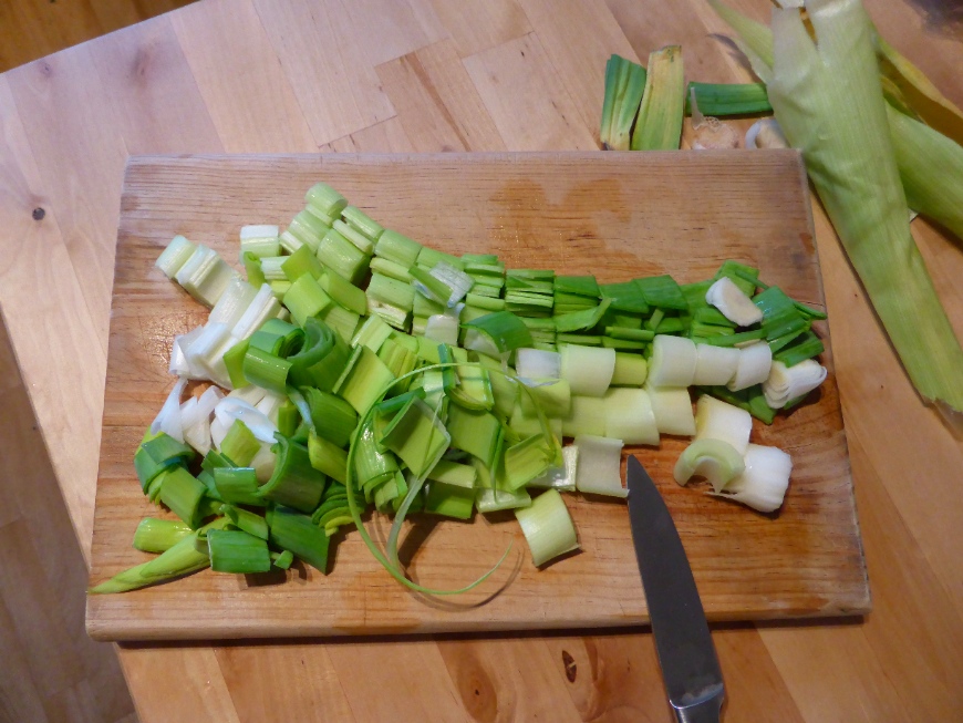 Slices leeks on a cutting board.