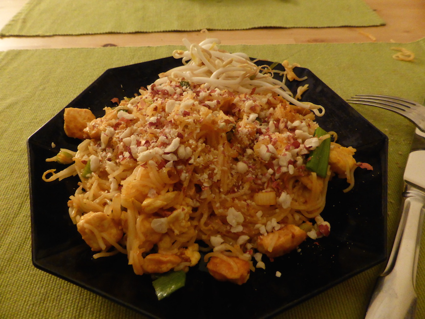 Pad thai in a plate with crushed peanuts and bean sprouts